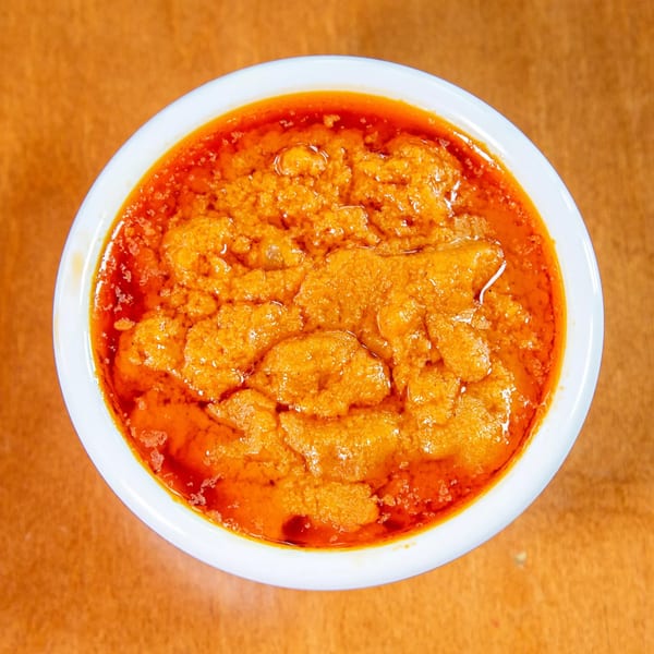 Overhead view of a white bowl filled with vibrant orange Ethiopian shiro stew.