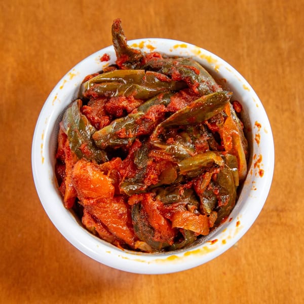 A white bowl filled with Ethiopian gomen, a dish of collard greens and red sauce.