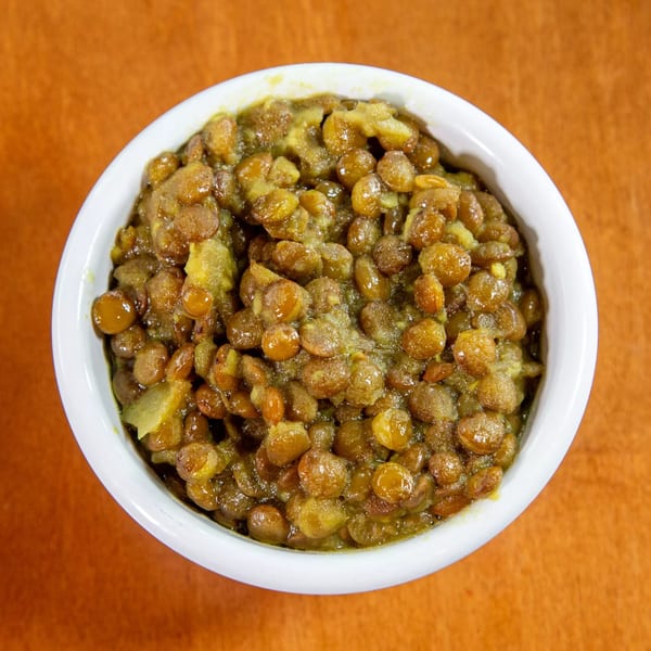 A white bowl filled with Ethiopian misir wot, a savory lentil stew, on an orange surface.