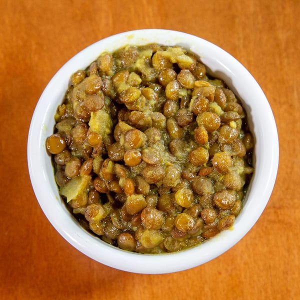 A white bowl filled with Ethiopian Misir Wot, a savory red lentil stew, on an orange surface.