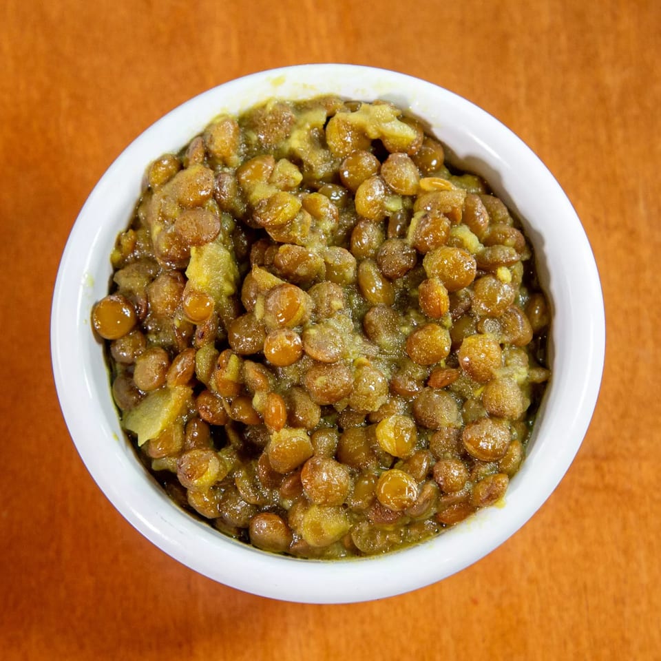 A white bowl filled with Ethiopian misir wot, a savory lentil stew, on an orange surface.